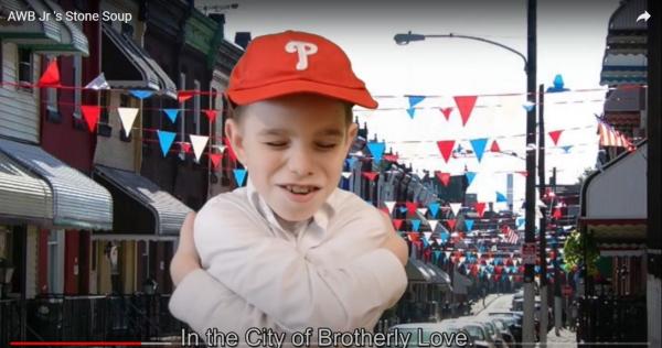 A video still of a young child wearing a Philly's cap - it looks like they are hugging themselves and the caption of the video clip reads "In the City of Brotherly Love"