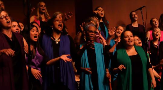 Large choir singing at a concert in colorful vests