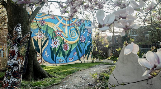 The Village's Ile Ife Park with murals and mosaics in the background and a blooming magnolia tree in the foreground
